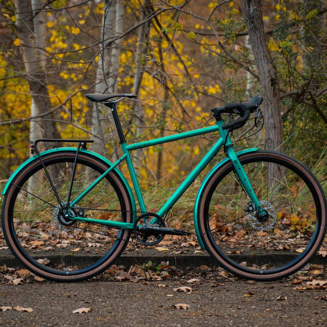 ein veloheld.alleyX Tourist in blaugrün steht vor vielen Bäumen