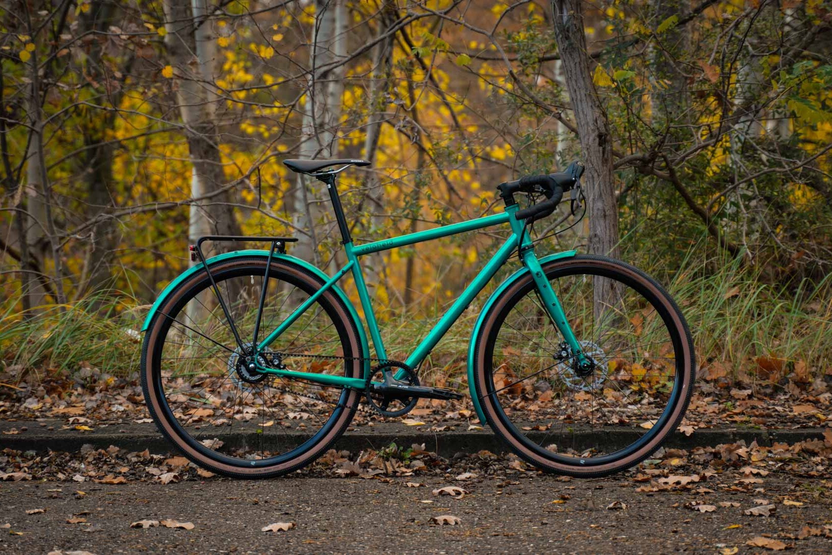 ein veloheld.alleyX Tourist in blaugrün steht vor vielen Bäumen