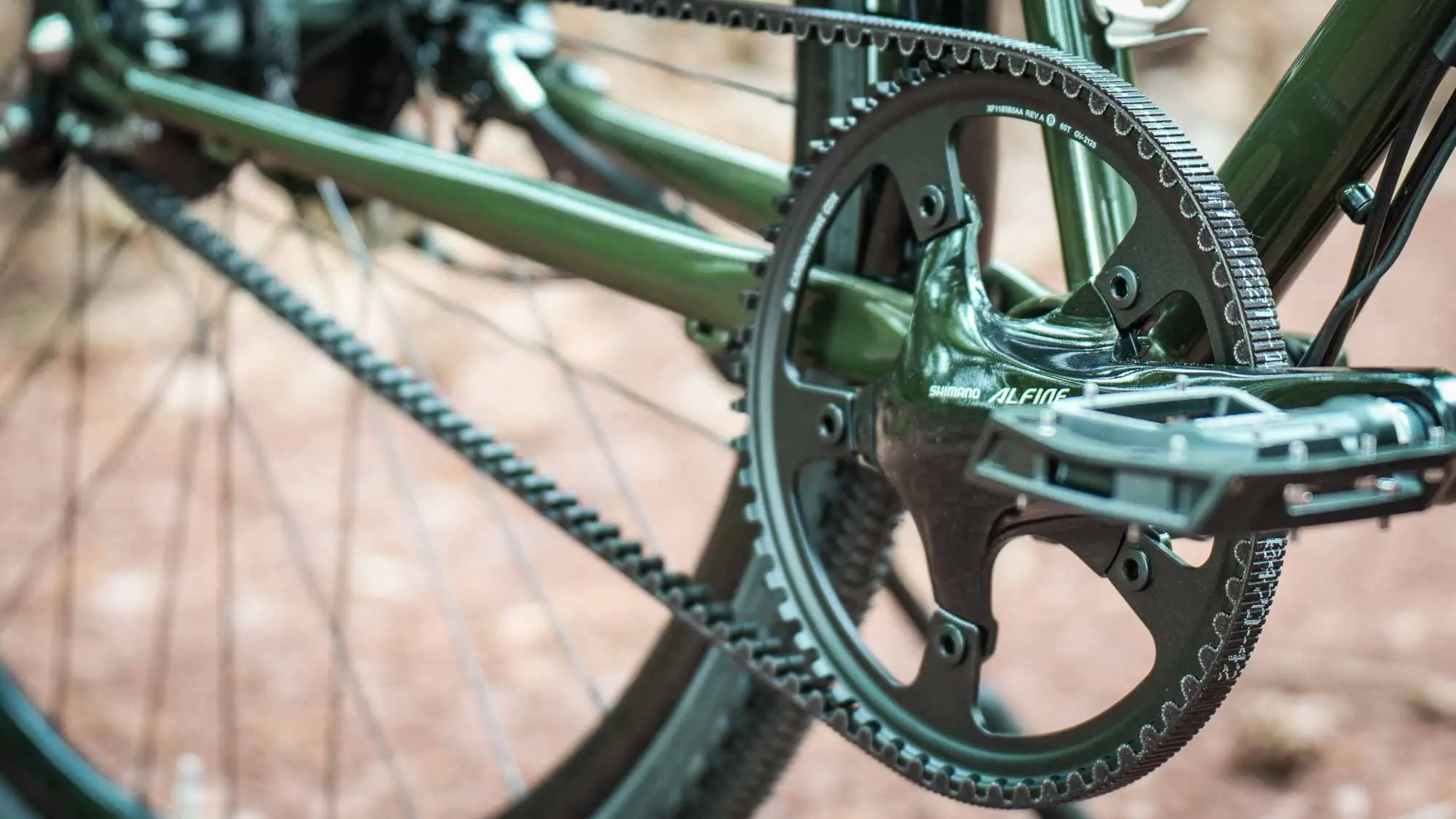 Detailaufnahme von Kurbel, Pedal und Gates Carbon Drive Riemenantrieb am grünen veloheld.alleyX mit Rohloff-Nabenschaltung.