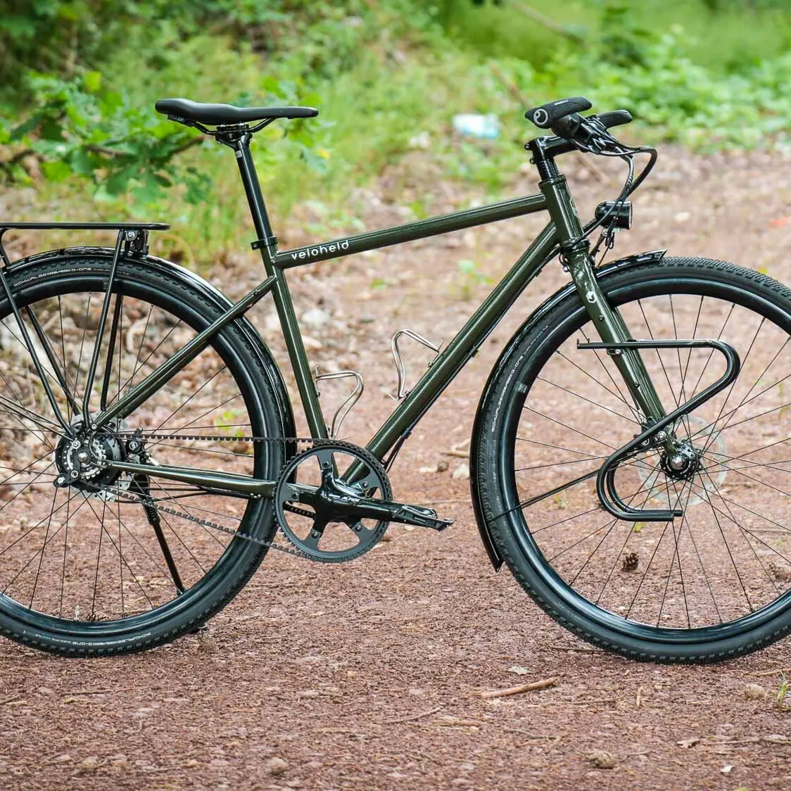 veloheld.alleyX Komplettrad mit Rohloff-Nabenschaltung, Schutzblechen und Gepäckträger als Komplettansicht auf einem Waldweg.