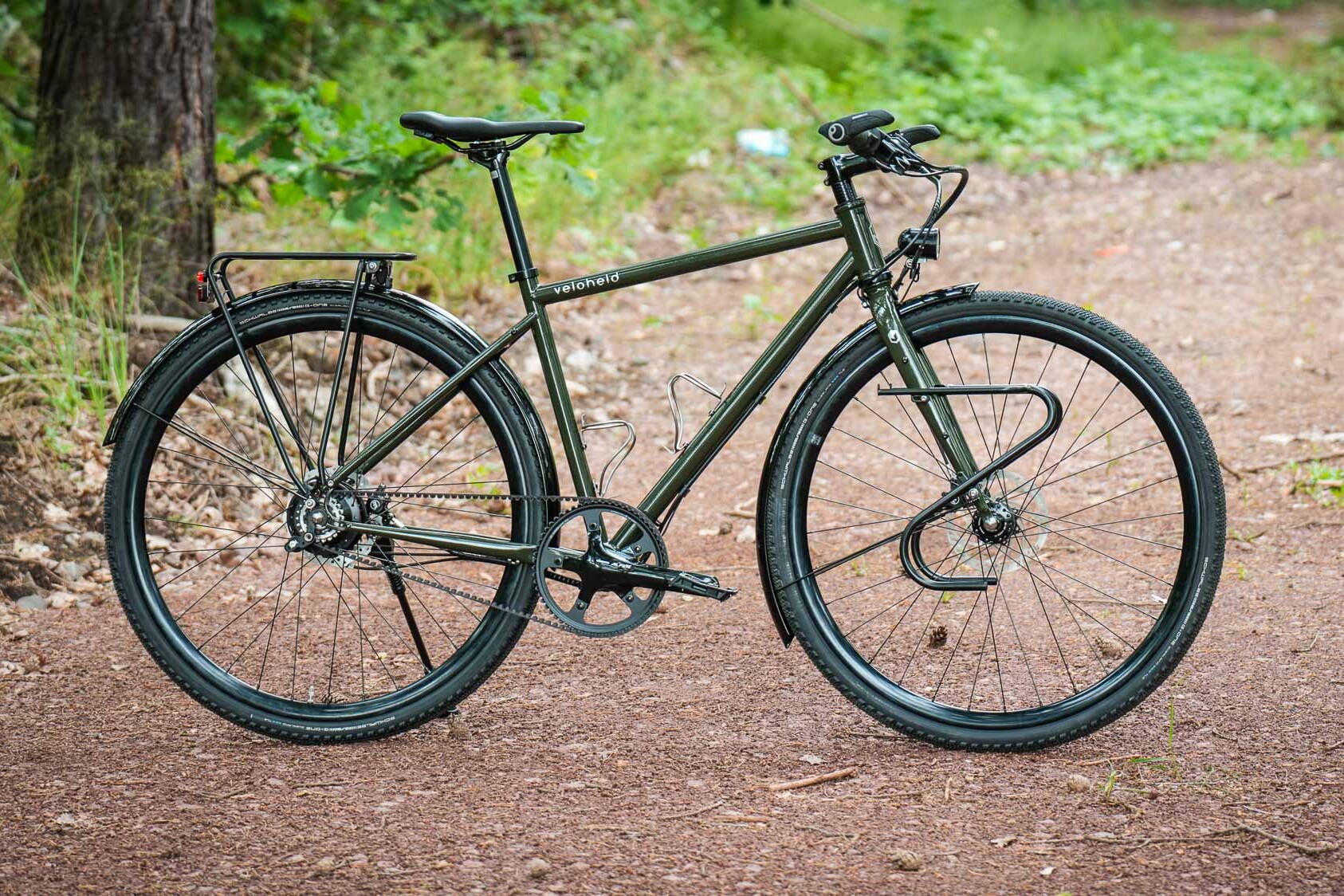 veloheld.alleyX Komplettrad mit Rohloff-Nabenschaltung, Schutzblechen und Gepäckträger als Komplettansicht auf einem Waldweg.